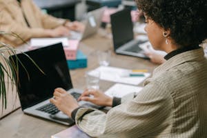 A professional woman using a laptop in a co-working space, focused on her task.